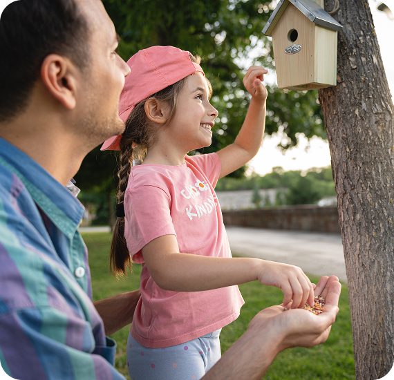 Child and parent feeding birds together happily.
