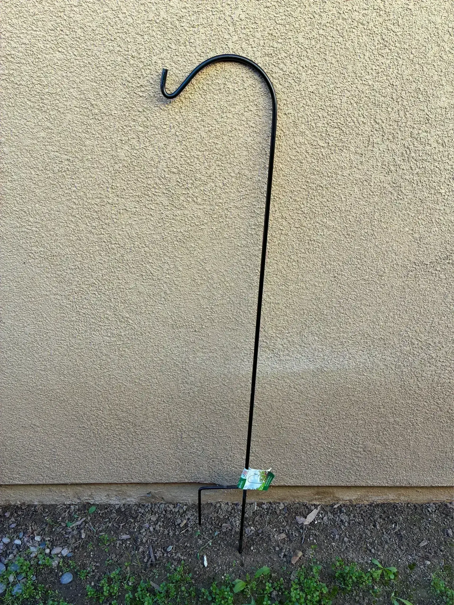 Black garden shepherd's hook in soil