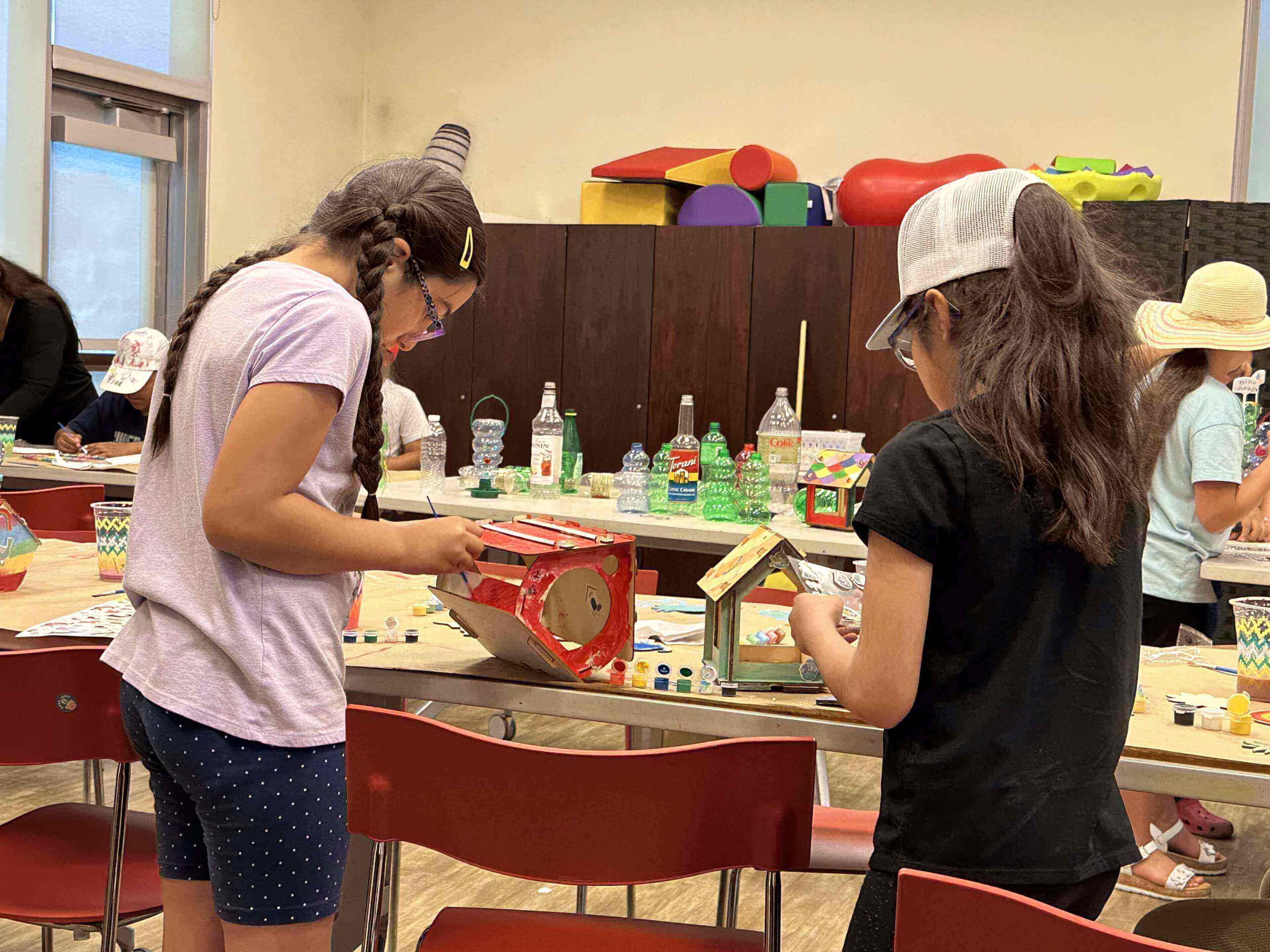 Two children painting small wooden houses
